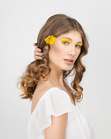 Pretty woman in white dress holding dandelion flowerの写真素材