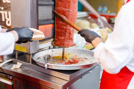 shawarma maker cuts meat with long knife to prepare wrapped meatの写真素材