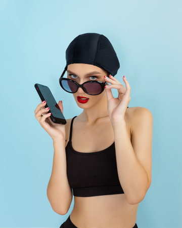 woman talking on the phone holds cellphone making answering call on isolated blue backgroundの写真素材