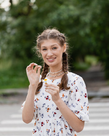 beautiful young woman with camomile against blue sky. Fortune-telling on a camomileの写真素材