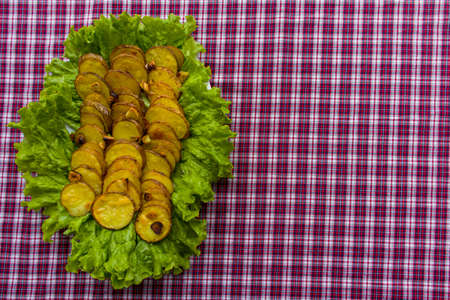 Cooked potato slices with salad on a table with red tableclothの写真素材