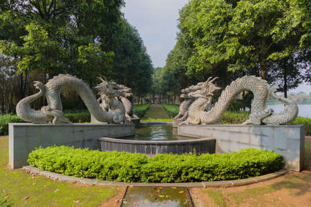 Four dragon statues in a public park with big fountain and green alleyの写真素材