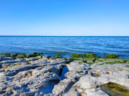 A landscape picture with clean blue sky, ocean and stone in front of.の写真素材