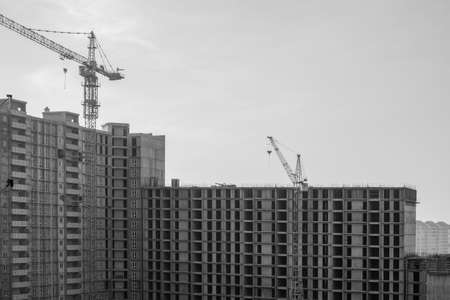 Construction of a large high-rise building with cranes with the grey sky background. Black and White.の写真素材
