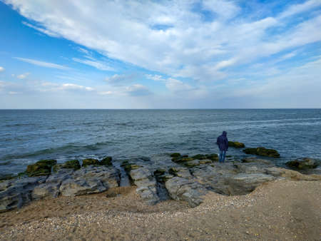 The silhouette of a man standing on the beach and looking into the water.の写真素材