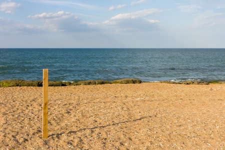 A long board stands stuck in the sand on the beach, with a clear blue sky.の写真素材