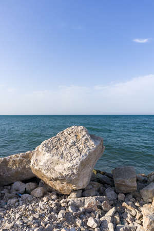 Large cobblestone lies on a rocky beach. With clean, blue sky background.