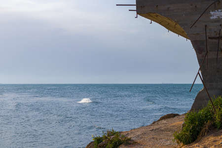 Sea wave near the beach with unfinished construction. Clean, blue sky on background.