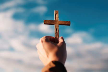 Conceptual image of a man holding a wooden cross over blue skyの素材