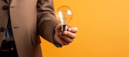 cropped view of businessman holding glowing light bulb on yellow background, idea conceptの素材