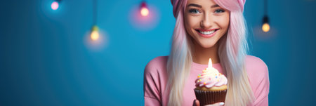 Beautiful young woman with pink hair holding cupcake and smiling at cameraの素材