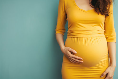 Pregnant woman in yellow dress on blue background, closeupの素材