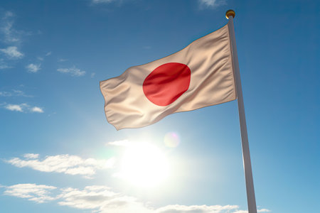 Japan flag waving in the wind against a blue sky with sun raysの素材