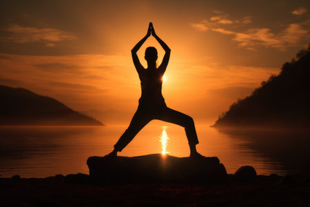 Silhouette of woman practicing yoga on the beach at sunrise.の素材