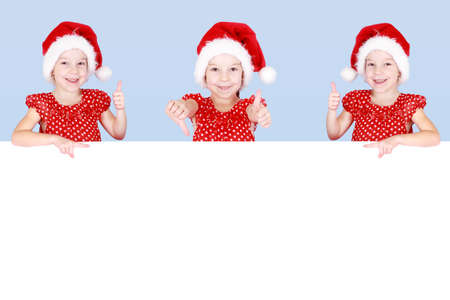 Girl in the hat of Santa Claus pointing the finger at the ad placeの写真素材