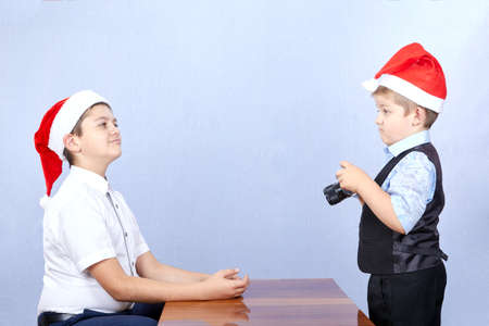 The younger brother in a cap of Santa Claus is photographing of brotherの写真素材