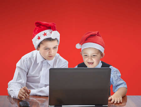 The brothers are sitting at the table and looking at a laptopの写真素材