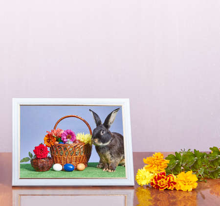 On a light background a photo in frame with a picture of the Easter basket and bunnyの写真素材