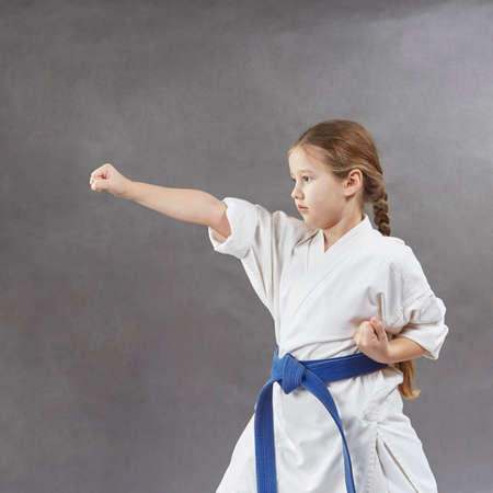 On a gray background the girl beats a blow with her handの写真素材