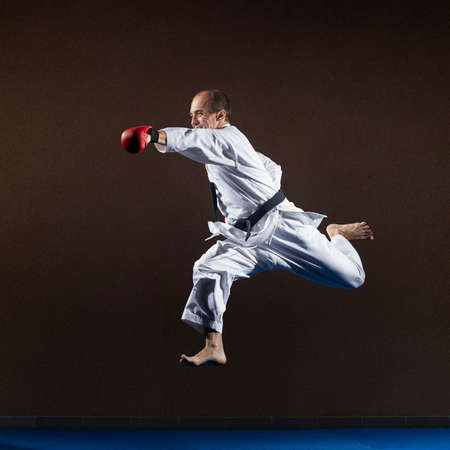 An athlete with red overlays on his hands trains a punch with his hand in a jumpの写真素材