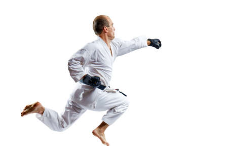 A man in black gloves trains a punch with his hand in a jump isolated