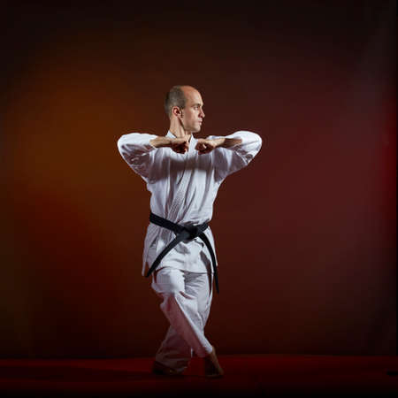 A man in karategi trains formal karate exercises on a dark backgroundの写真素材