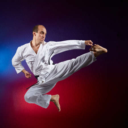 The athlete beats a kick in the jump on a red and blue backgroundの写真素材