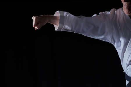 Hand punch performed by an adult athlete with a black belt on a dark backgroundの写真素材