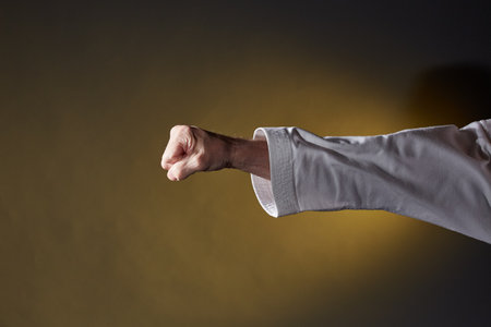 Against a dark yellow background, punch and block hand in karategiの写真素材