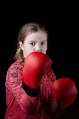 Little athlete with red overlays on her hands on a black backgroundの写真素材