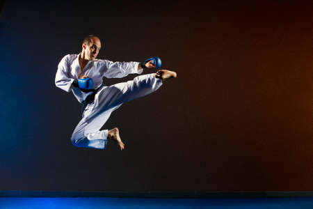 A man with blue overlays on his hands beats a kick in a jumpの写真素材