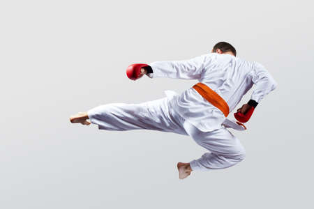 Man with red overlays on his hands trains a kick on a light backgroundの写真素材