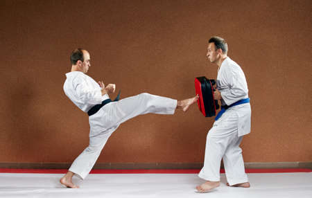 A sportsman with a black belt beats his kick on the simulatorの写真素材