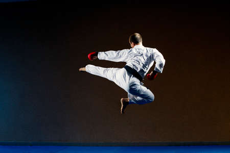 A man in karategi trains a kicking in a jumpの写真素材