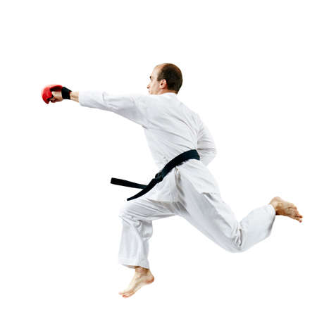 On a white background, an adult athlete in karategi beats with a hand in the jumpの写真素材
