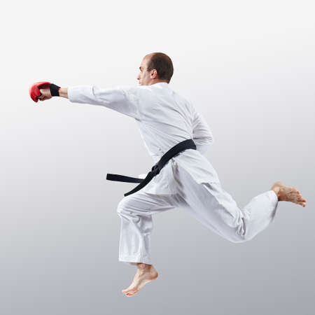 On a light background, an athlete in karategi trains a jab in jumpの写真素材