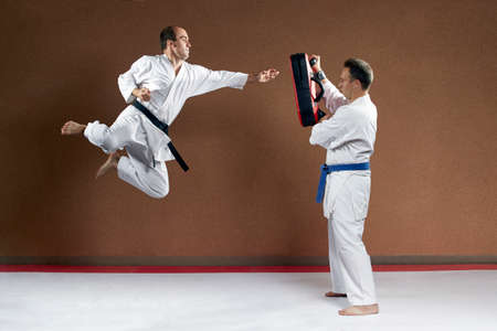 An athlete with a blue belt holds a simulator on which to strike another the athleteの写真素材