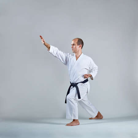 On a gray background, an adult sportsman trains a formal karate exerciseの写真素材