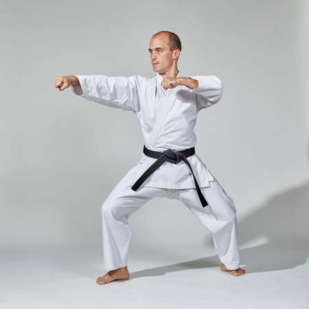 On a gray background, a young athlete performs formal karate exercisesの写真素材