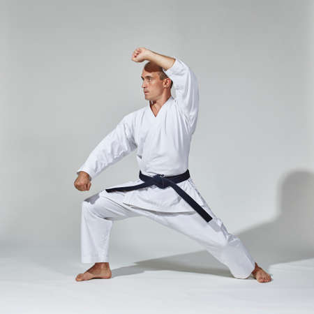 On a gray background, a young athlete trains a formal karate exerciseの写真素材
