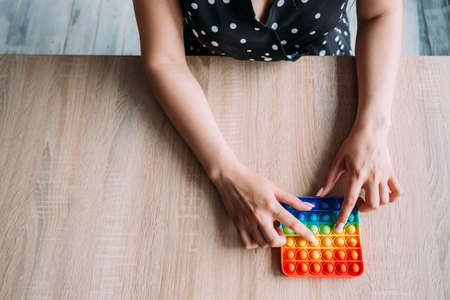 Young girl, dressed in a polka-dot dress, presses on a pop-it anti-stress toyの写真素材