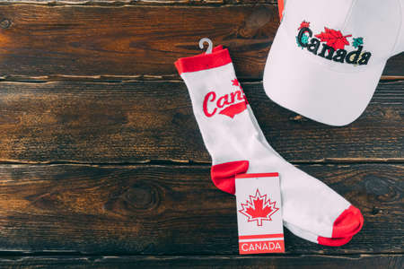 White baseball cap and socks with the inscription Canada on a wooden background