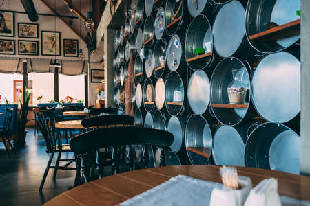 ZATOKA, UKRAINE - JUNE 14 2021: The interior of the restaurant's pub is in a modern retro style with a predominance of wood and metal finishes. On the right is a rack with metal basinsのeditorial素材