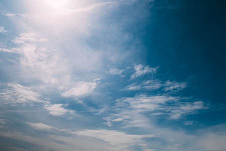 Blue sky with clouds through which the sun shines throughの写真素材