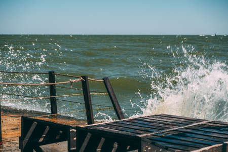Close-up of dark brown sun loungers on a concrete slab by the sea.