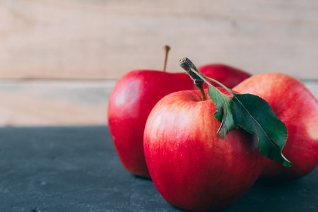 Several apples close-up on a gray table against a background of boards. Copy space