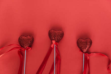 Three hearts with ribbons on sticks on a red background. Valentine's day concept. Relationship, loveの写真素材