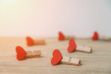 Several clothespins with hearts lie on a light wooden table. Love and relationships.の写真素材