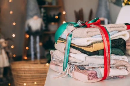 Winter woolen hats and blankets of different colors in a gift ribbon. Gift for New Year and Christmas. Copy space. Idea for a family gift.の写真素材