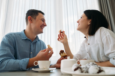 Portrait of happy guy and girl at home in kitchen. Morning breakfast for couple. Kind, sparkling emotions. Home comfort.の写真素材